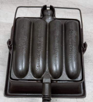 Wagner Krusty Korn Sausage Pan with patent numbers, with High Base. Sold for $700. Alaskan wire handles, bailed handle on base. 